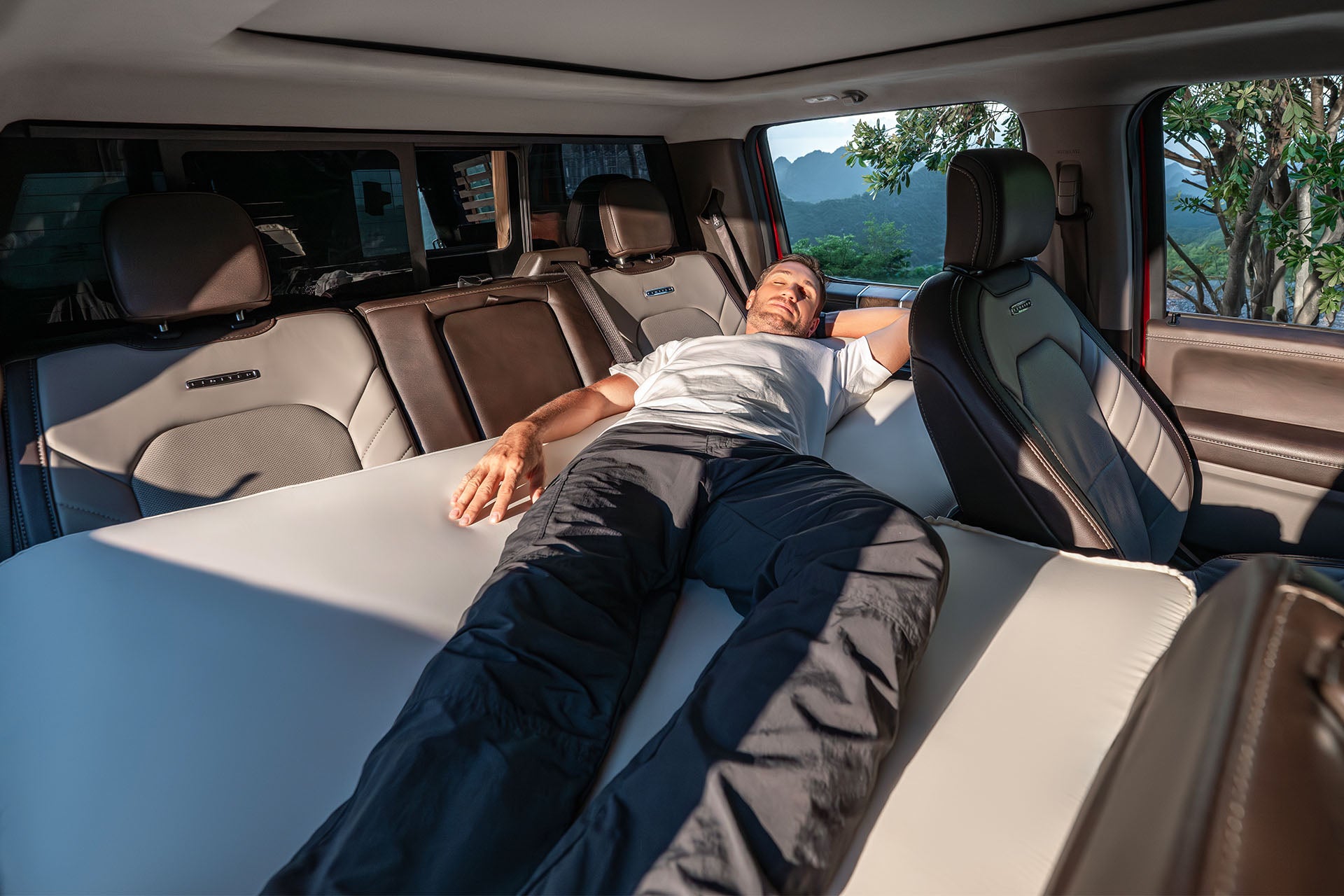 Tall man sleeping diagonally with dog on Havnby extending pad for CozyPad mattress.